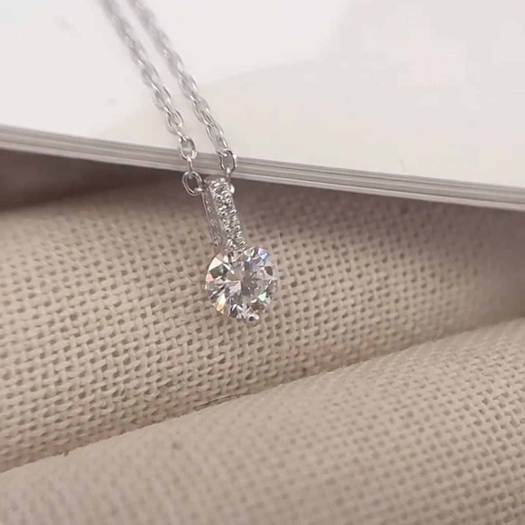 Luna Solitaire Moissanite Necklace, close-up of the round moissanite and pavé bar on natural linen