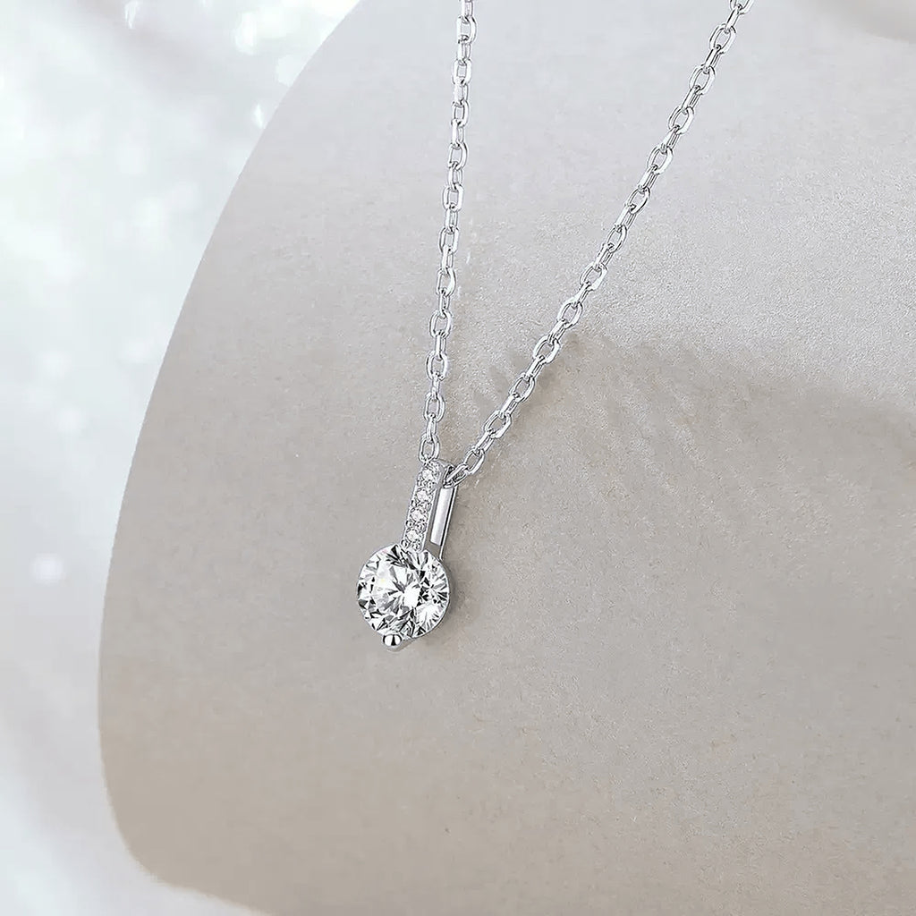 Luna Solitaire Moissanite Necklace, round moissanite pendant on a fine S925 sterling silver chain in a soft studio scene